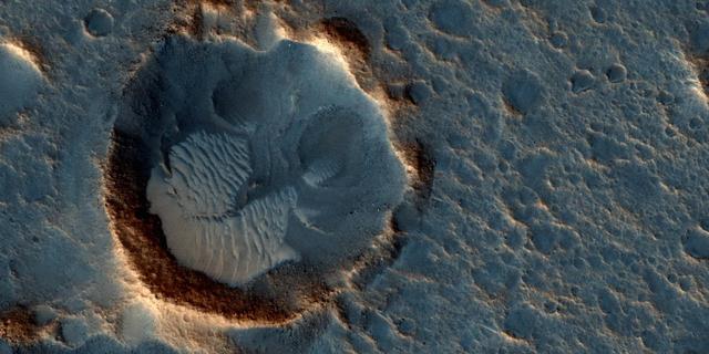 This image from the High Resolution Imaging Science Experiment (HiRISE) camera on NASA's Mars Reconnaissance Orbiter shows a location on Mars associated with the best-selling novel and Hollywood movie, "The Martian." This area is in the Acidalia Planitia region. In the novel and the movie, it is the landing site of a crewed mission named Ares 3. For the story's central character, Acidalia Planitia is within driving distance from where NASA's Mars Pathfinder, with its Sojourner rover, landed in 1997. An initial HiRISE image of the site was taken in April 2015 and is online at http://hirise.lpl.arizona.edu/ESP_040776_2115. A second one was taken May 17, 2015, and is shown here. Figure 1 is a stereo combination of the two, appearing three-dimensional when viewed through blue-red glasses with the red lens on the left One of the main objectives of the HiRISE camera is to carry out "monitoring science", which involves taking images of certain areas of high scientific interest on regular intervals. The team usually does so to monitor a seasonal or recurring process such as seasonal changes in carbon-dioxide ice near the poles, dune movement or recurring flow-like features on some slopes. HiRISE also takes repeated images of areas with active rovers, such as Curiosity, to help plan safe routes toward areas of high scientific interest. Another key responsibility for the HiRISE camera is to provide information for use in selection of landing sites for future missions. One technique is to image a site of interest at least twice when the weather conditions are similar, but with a small difference in viewing angle, much like what you would experience if you looked at something with only your right eye, then looked at it again with the left. By doing this, we are able to build a stereo view of the site, providing a chance to identify high and low points in the site more effectively. This resulting 3-D information can combined with elevation data from laser altimeters to create a highly accurate "digital terrain model" or DTM for short. DTMs allow researchers to view the locations in 3-D and to analyze them by measuring the exact height of features that could be hazardous to the future mission, such as large boulders or small impact craters. DTMs from HiRISE were a key factor in choosing the landing site for NASA's Curiosity Mars rover in Gale Crater and are being used to evaluate sites under consideration for the NASA's 2016 InSight Mars lander and Mars 2020 rover missions. The location of the site in this image is 31.3 degrees north latitude, 331.3 degrees east latitude. The image is an excerpt from HiRISE observation ESP_041277_2115. http://photojournal.jpl.nasa.gov/catalog/PIA19913