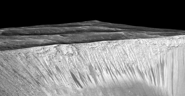 Dark narrow streaks, called "recurring slope lineae," emanate from the walls of Garni Crater on Mars, in this view constructed from observations by the High Resolution Imaging Science Experiment (HiRISE) camera on NASA's Mars Reconnaissance Orbiter. The dark streaks here are up to few hundred yards, or meters, long. They are hypothesized to be formed by flow of briny liquid water on Mars. The image was produced by first creating a 3-D computer model (a digital terrain map) of the area based on stereo information from two HiRISE observations, and then draping an image over the land-shape model. The vertical dimension is exaggerated by a factor of 1.5 compared to horizontal dimensions. The draped image is a red waveband (monochrome) product from HiRISE observation ESP_031059_1685, taken on March 12, 2013 at 11.5 degrees south latitude, 290.3 degrees east longitude. Other image products from this observation are at http://hirise.lpl.arizona.edu/ESP_031059_1685. http://photojournal.jpl.nasa.gov/catalog/PIA19917