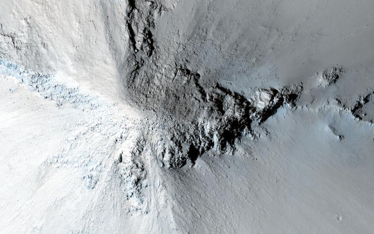 There are many hills and knobs on Mars that reveal aspects of the local geologic history. Typically, the hills in the relatively-smooth region surrounding this image are flat topped erosional remnants or mesas with irregular or even polyhedral margins. These landforms suggest wide spread erosion of the soft or weakly-cemented sedimentary layers. This hill stands out because of is circular inverted-cone shape and apparent dark streaks along its flanks visible in lower resolution images. Close inspection from HiRISE reveals that the fine soils sloping down from the peak are intersected with radiating lines of rock and eroding rubble. This formation is similar to lava intrusions that form in the core of a volcano. As lava is squeezed up into a central conduit, radiating fractures fill with lava forming rock units called dikes. As the lava cools inside the ground and in the fractures, it forms into a harder rock that is more resistant to erosion. Later, as the surrounding sediments and soils erode, the resistant volcanic rock remains standing to tell a story of what happened underground long ago. http://photojournal.jpl.nasa.gov/catalog/PIA20003