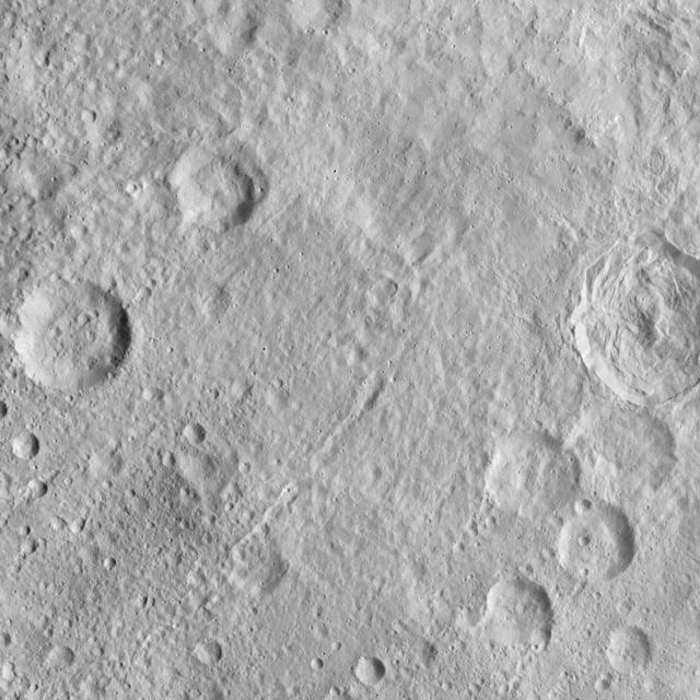 This image, taken by NASA's Dawn spacecraft, displays a linear structure trending from northeast to southwest (lower left to upper right). The graben -- what geologists call a linear feature where terrain has dropped -- might be interpreted as a chain of collapsed pits or secondary craters. The crater at center right displays terraced walls, a common feature among the impact sites of Ceres. The image was taken on Oct. 6, 2015, from an altitude of 915 miles (1,470 kilometers). It has a resolution of 450 feet (140 meters) per pixel. The image is located at 31 degrees north latitude, 120 degrees east longitude. http://photojournal.jpl.nasa.gov/catalog/PIA20123