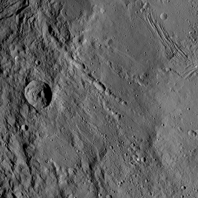 This view from NASA's Dawn spacecraft shows different types of terrain located side by side on Ceres: a smooth terrain at right with numerous small impact craters, and a less-cratered, hummocky terrain at left. A huge crater chain crosses the scene diagonally from upper left to lower right.  The smooth terrain, which is in the western part of Yalode impact basin, is interrupted by a set of roughly parallel furrows and ridges at upper right. These linear features are perpendicular to another set of smaller, fainter linear markings, which appear just below them.  An impact into the hummocky terrain formed a crater, seen at left, 14 miles (22 kilometers) in diameter with a central peak. A great deal of material has slumped down the walls of the crater -- a phenomenon called mass wasting. The crater's impact ejecta forms a smooth blanket around its rim, which takes on a streaky texture leading away from the crater toward lower right.  The image was taken during in Dawn's High Altitude Mapping Orbit (HAMO) phase from an altitude of 911 miles (1,466 kilometers) on Oct. 6, 2015. Image resolution is 394 feet (120 meters) per pixel. The image is centered at 37 degrees south latitude, 279 degrees east longitude.  http://photojournal.jpl.nasa.gov/catalog/PIA20133
