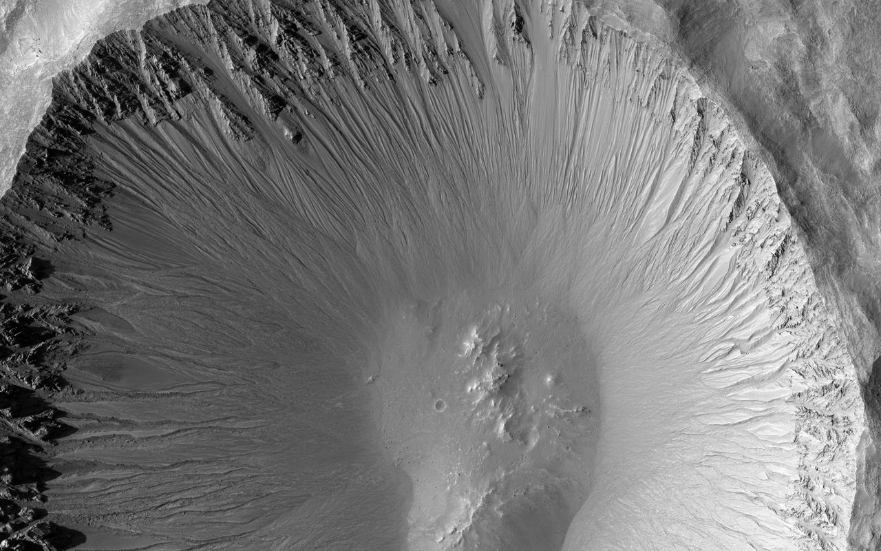 The central portion of this image from NASA's Mars Reconnaissance Orbiter is dominated by a sharp-rimmed crater that is roughly 5 kilometers in diameter. On its slopes, gullies show young (i.e., geologically recent) headward erosion, which is the lengthening of the gully in the upslope direction. This crater is also remarkable for another reason. This image is part of a stereo pair, and the anaglyph of these images shows that the bottom of the crater contains a small mound. This mound hints at a possible complex crater, with the mound being a central uplift. Complex craters as small as this one are uncommon and such examples may provide clues to the lithology of the rocks underground and possibly to the impact process itself. http://photojournal.jpl.nasa.gov/catalog/PIA20158