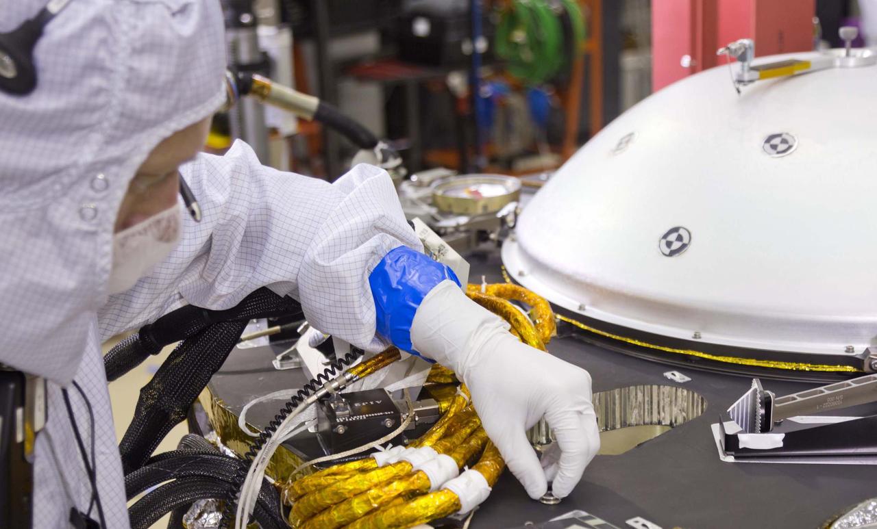 A spacecraft specialist in a clean room at Lockheed Martin Space Systems in Denver affixes a dime-size chip onto the lander deck in November 2015. This chip carries 826,923 names, submitted by the public online from all over the world.