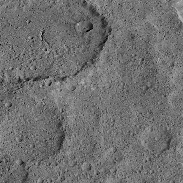 This view of Ezinu Crater on Ceres was taken by NASA's Dawn spacecraft on Oct. 19, 2015. Ezinu is the large crater in the top left corner of the image. The crater is 72 miles (116 kilometers) wide and contains a canyon-like feature near its center. The image was taken from a spacecraft altitude of 915 miles (1,470 kilometers) during Dawn's High Altitude Mapping Orbit (HAMO) phase. Image resolution is 450 feet (140 meters) per pixel. The image is centered at approximately 37 degrees north latitude, 200 degrees east latitude. http://photojournal.jpl.nasa.gov/catalog/PIA20190
