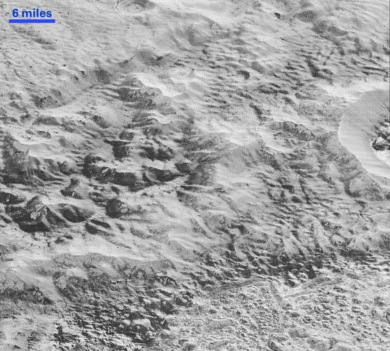 This highest-resolution image from NASA's New Horizons spacecraft shows how erosion and faulting has sculpted this portion of Pluto's icy crust into rugged badlands. The prominent 1.2-mile-high cliff at the top, running from left to upper right, is part of a great canyon system that stretches for hundreds of miles across Pluto's northern hemisphere. New Horizons team members think that the mountains in the middle are made of water ice, but have been modified by the movement of nitrogen or other exotic ice glaciers over long periods of time, resulting in a muted landscape of rounded peaks and intervening sets of short ridges. At the bottom of this 50-mile-wide image, the terrain transforms dramatically into a fractured and finely broken up floor at the northwest margin of the giant ice plain informally called Sputnik Planum. The top of the image is to Pluto's northwest.  These images were made with the telescopic Long Range Reconnaissance Imager (LORRI) aboard New Horizons, in a timespan of about a minute centered on 11:36 UT on July 14 -- just about 15 minutes before New Horizons' closest approach to Pluto -- from a range of just 10,000 miles (17,000 kilometers). They were obtained with an unusual observing mode; instead of working in the usual "point and shoot," LORRI snapped pictures every three seconds while the Ralph/Multispectral Visual Imaging Camera (MVIC) aboard New Horizons was scanning the surface. This mode requires unusually short exposures to avoid blurring the images.  http://photojournal.jpl.nasa.gov/catalog/PIA20199