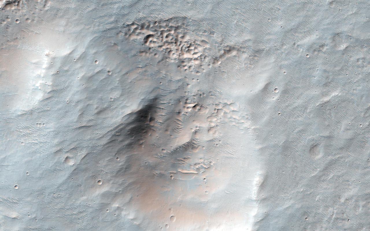 This image from NASA Mars Reconnaissance Orbiter spacecraft shows an interesting collection of kilometer-scale craters with flat and smooth floors. The craters themselves may be the result of secondary impacts, craters caused by debris from a distant larger impact. Since then, the surface has been significantly modified and reworked, muting the craters and flattening their floors.  Presently, there are a few sand dunes and a broad overlay of a dusty soil mantle. This soil mantle occurs over much of the middle latitudes of Mars. Here, as elsewhere, the mantle covers these craters, but a closer inspection reveals that its smooth texture becomes significantly pitted and bumpy on the pole facing slopes of each crater interior wall. http://photojournal.jpl.nasa.gov/catalog/PIA20288