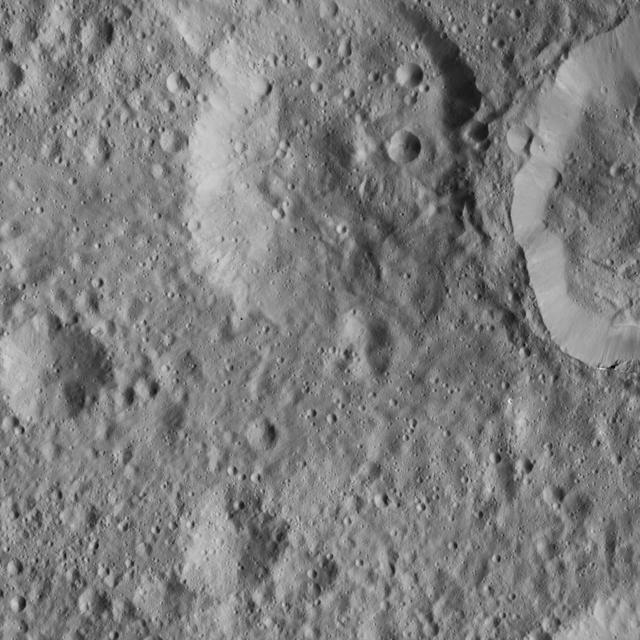 This scene from Ceres, captured by NASA Dawn spacecraft, shows an older crater at top center that has been blanketed by impact ejecta from the younger crater to its right.