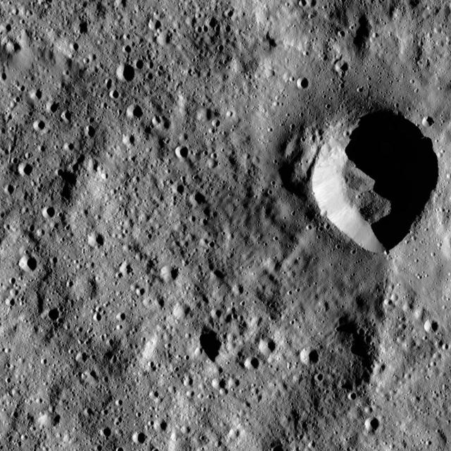 This image from NASA Dawn spacecraft shows a fresh impact crater with an asymmetric rim. The crater displays a sharp rim over much of its perimeter that is interrupted by a smooth area in the north.