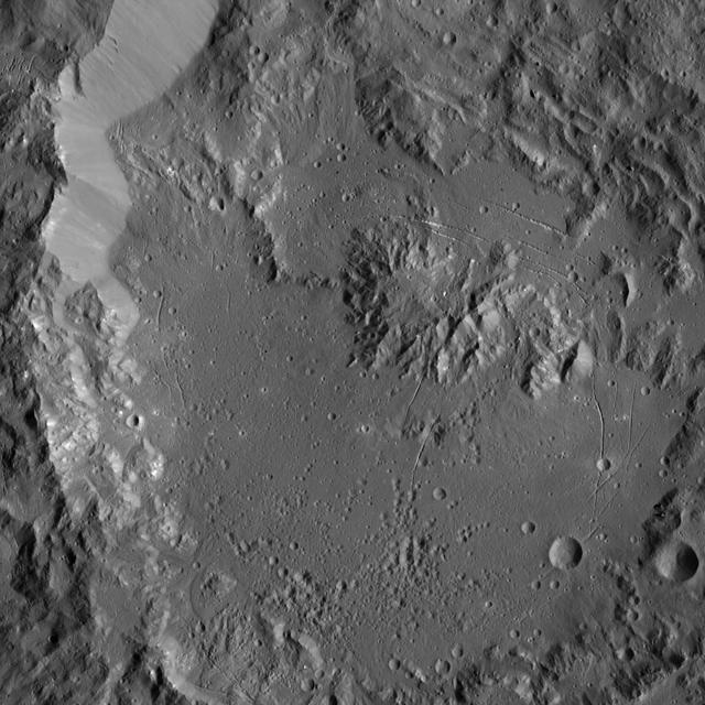 This image, taken by NASA Dawn spacecraft, shows Ikapati Crater with its complex of central peaks on Ceres. Several groupings of roughly parallel fractures are present in smooth areas of the crater floor.