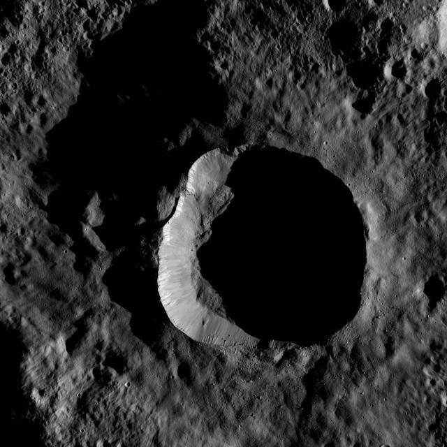 This view from NASA Dawn spacecraft shows an impact site at high southern latitude on Ceres. A smooth blanket of ejecta surrounds the crater. Many boulders can be seen around the crater rim and on the sunlit part of its floor.