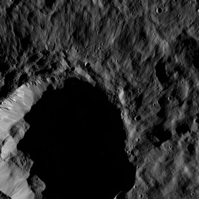 This view from NASA Dawn spacecraft shows a moderate-sized impact feature that is imprinted upon the southern rim of Mondamin Crater. Boulders of various sizes can be seen around the crater rim and on the sunlit part of its floor.