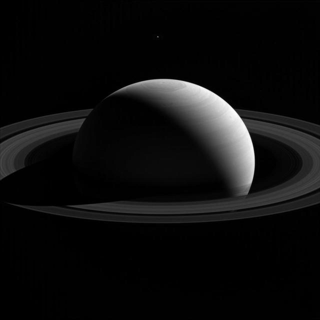 An illusion of perspective, Saturn's moon Tethys seems to hang above the planet's north pole in this view from NASA's Cassini spacecraft. Tethys (660 miles or 1,062 kilometers across) is actually farther away than Saturn in this image. Lacking visual clues about distance, our brains place the moon above Saturn's north pole. Tethys, like all of Saturn's major moons and its ring system, orbits almost exactly in the planet's equatorial plane. This view looks toward the sunlit side of the rings from about 17 degrees above the ring plane. The image was taken with the Cassini spacecraft's wide-angle camera on Jan. 26, 2015 using a spectral filter which preferentially admits wavelengths of near-infrared light centered at 752 nanometers. The view was acquired at a distance of approximately 2.1 million miles (3.4 million kilometers) from Saturn. Image scale on Saturn is 120 miles (200 kilometers) per pixel. Tethys has been brightened by a factor of three relative to Saturn to enhance its visibility. http://photojournal.jpl.nasa.gov/catalog/PIA20488