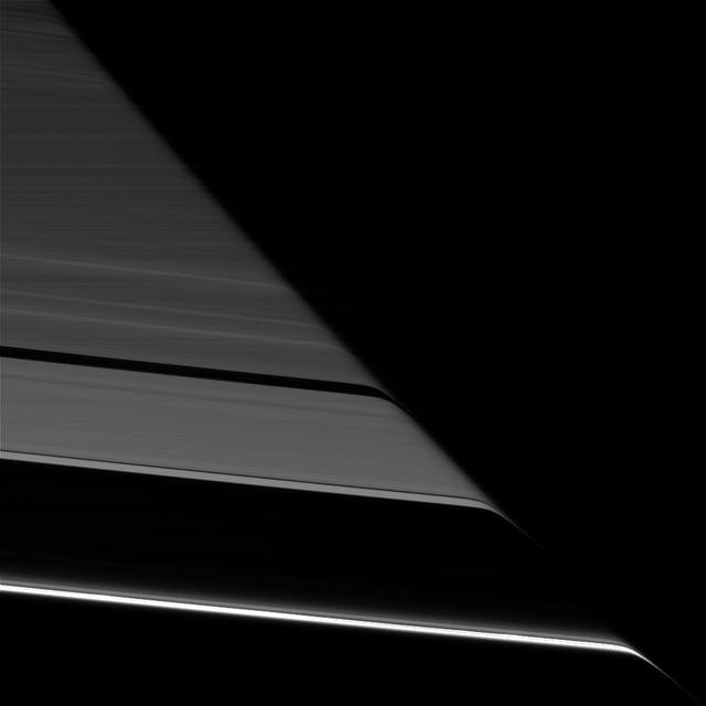 Saturn's rings appear to bend as they pass behind the planet's darkened limb due to refraction by Saturn's upper atmosphere. The effect is the same as that seen in an earlier Cassini view (see PIA20491), except this view looks toward the unlit face of the rings, while the earlier image viewed the rings' sunlit side. The difference in illumination brings out some noticeable differences. The A ring is much darker here, on the rings' unlit face, since its larger particles primarily reflect light back toward the sun (and away from Cassini's cameras in this view). The narrow F ring (at bottom), which was faint in the earlier image, appears brighter than all of the other rings here, thanks to the microscopic dust that is prevalent within that ring. Small dust tends to scatter light forward (meaning close to its original direction of travel), making it appear bright when backlit. (A similar effect has plagued many a driver with a dusty windshield when driving toward the sun.) This view looks toward the unilluminated side of the rings from about 19 degrees below the ring plane. The image was taken in red light with the Cassini spacecraft narrow-angle camera on July 24, 2016. The view was acquired at a distance of approximately 527,000 miles (848,000 kilometers) from Saturn and at a sun-Saturn-spacecraft, or phase, angle of 169 degrees. Image scale is 3 miles (5 kilometers) per pixel. http://photojournal.jpl.nasa.gov/catalog/PIA20497