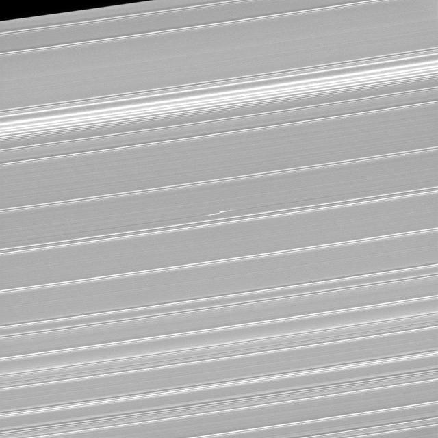 What appears as a pair of bright dashes at the center of this image is one of the features rings scientists have dubbed "propellers." This particular propeller, named Bleriot, marks the presence of a body that is much larger than the particles that surround it, yet too small to clear out a complete gap in the rings (like Pan and Daphnis) and become a moon in its own right. Although the moonlet at the core of the propeller is itself too small to see, the disturbances in the rings caused by its gravity betray its presence. Cassini scientists have been tracking propeller features like this one for years in order to learn how their orbits change over time. From this, they hope to gain insight into how forming planets migrate in the disks in which they form. This view looks toward the sunlit side of the rings from about 59 degrees above the ring plane. The image was taken in visible light with the Cassini spacecraft narrow-angle camera on Jan. 9, 2017. The view was acquired at a distance of approximately 223,000 miles (359,000 kilometers) from Saturn and at a Sun-Saturn-spacecraft, or phase, angle of 73 degrees. Image scale is 1.2 miles (2 kilometers) per pixel. http://photojournal.jpl.nasa.gov/catalog/PIA20525