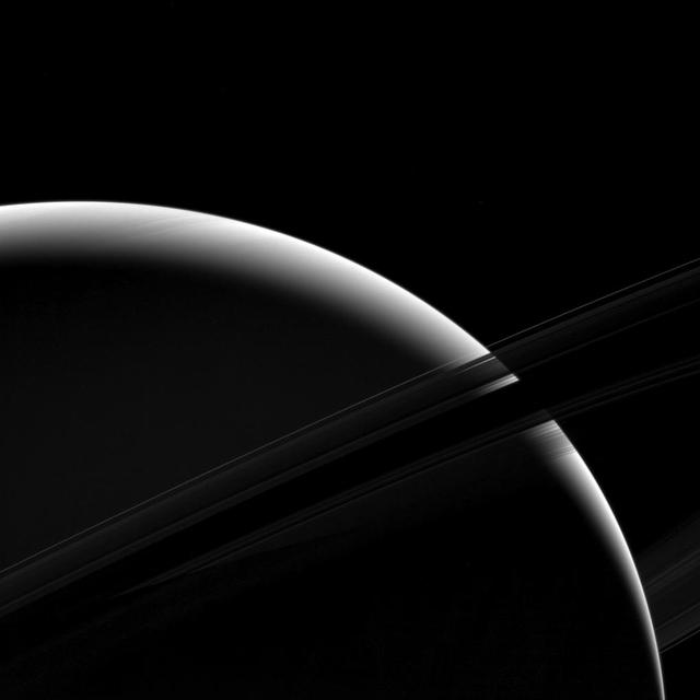 Although only a sliver of Saturn's sunlit face is visible in this view, the mighty gas giant planet still dominates the view.  From this vantage point just beneath the ring plane, the dense B ring becomes dark and essentially opaque, letting almost no light pass through. But some light reflected by the planet passes through the less dense A ring, which appears above the B ring in this photo. The C ring, silhouetted just below the B ring, lets almost all of Saturn's reflected light pass right through it, as if it were barely there at all. The F ring appears as a bright arc in this image, which is visible against both the backdrop of Saturn and the dark sky.   This view looks toward the unilluminated side of the rings from about 7 degrees below the ring plane. The image was taken in green light with the Cassini spacecraft wide-angle camera on Jan. 18, 2017.  The view was acquired at a distance of approximately 630,000 miles (1 million kilometers) from Saturn. Image scale is 38 miles (61 kilometers) per pixel.  https://photojournal.jpl.nasa.gov/catalog/PIA20530