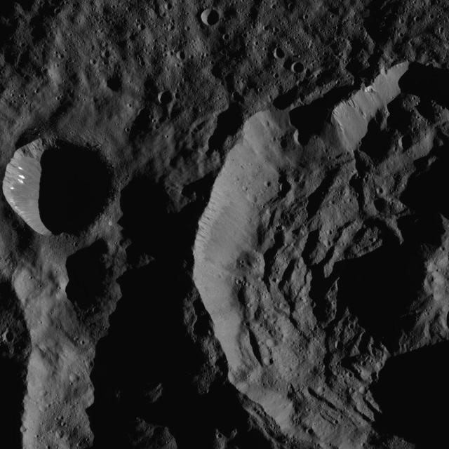 This image shows Sekhet Crater, at right, in a shadowy scene from Ceres. Sekhet is 25 miles wide 41 kilometers wide. NASA Dawn spacecraft took this image on June 15, 2016. A smooth plain surrounds the smaller crater at left. A smooth plain surrounds the smaller crater at left. A different view of this crater can be found at PIA20390.  Dawn took this image from its low-altitude mapping orbit, at a distance of about 240 miles (385 kilometers) above the surface. The image resolution is 120 feet (35 meters) per pixel. This view is centered at approximately 67 degrees south latitude, 249 degrees east longitude.  http://photojournal.jpl.nasa.gov/catalog/PIA20828