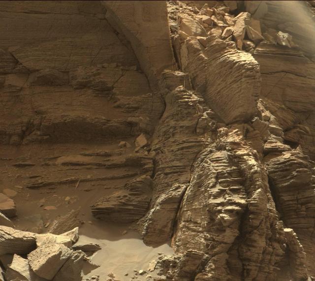 This view from the Mast Camera (Mastcam) in NASA's Curiosity Mars rover shows an outcrop with finely layered rocks within the "Murray Buttes" region on lower Mount Sharp.  The buttes and mesas rising above the surface in this area are eroded remnants of ancient sandstone that originated when winds deposited sand after lower Mount Sharp had formed. Curiosity closely examined that layer -- called the "Stimson formation" -- during the first half of 2016, while crossing a feature called "Naukluft Plateau" between two exposures of the Murray formation. The layering within the sandstone is called "cross-bedding" and indicates that the sandstone was deposited by wind as migrating sand dunes.  The image was taken on Sept. 8, 2016, during the 1454th Martian day, or sol, of Curiosity's work on Mars.   http://photojournal.jpl.nasa.gov/catalog/PIA21044