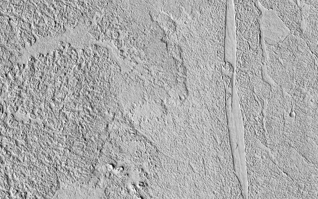 This image shows some beautiful lava flows in Amazonis Planitia. Lava isn't moving around on Mars today, but it certainly once did, and images like this one are evidence of that.  A thick lava flow came in from the west, and you can see the cooled flow lobes and wrinkled upper surface. East of the flow margin, this most recent flow also coursed over an older lava surface which shows some long, north-south breaks, and in the southeast corner, an arrowhead-shaped set of ridges. These textures are most likely from rafted slabs of lava. Under certain conditions, a large piece of lava can cool, but then detach and move like an iceberg over a cushion of still-molten lava.  The long, narrow north-south smooth areas are probably where two of these plates rafted away from one another exposing the lava below. The arrowhead-shaped ridges are probably from when one of these plates pushed up against another one and caused a pile-up before cooling.  http://photojournal.jpl.nasa.gov/catalog/PIA21113
