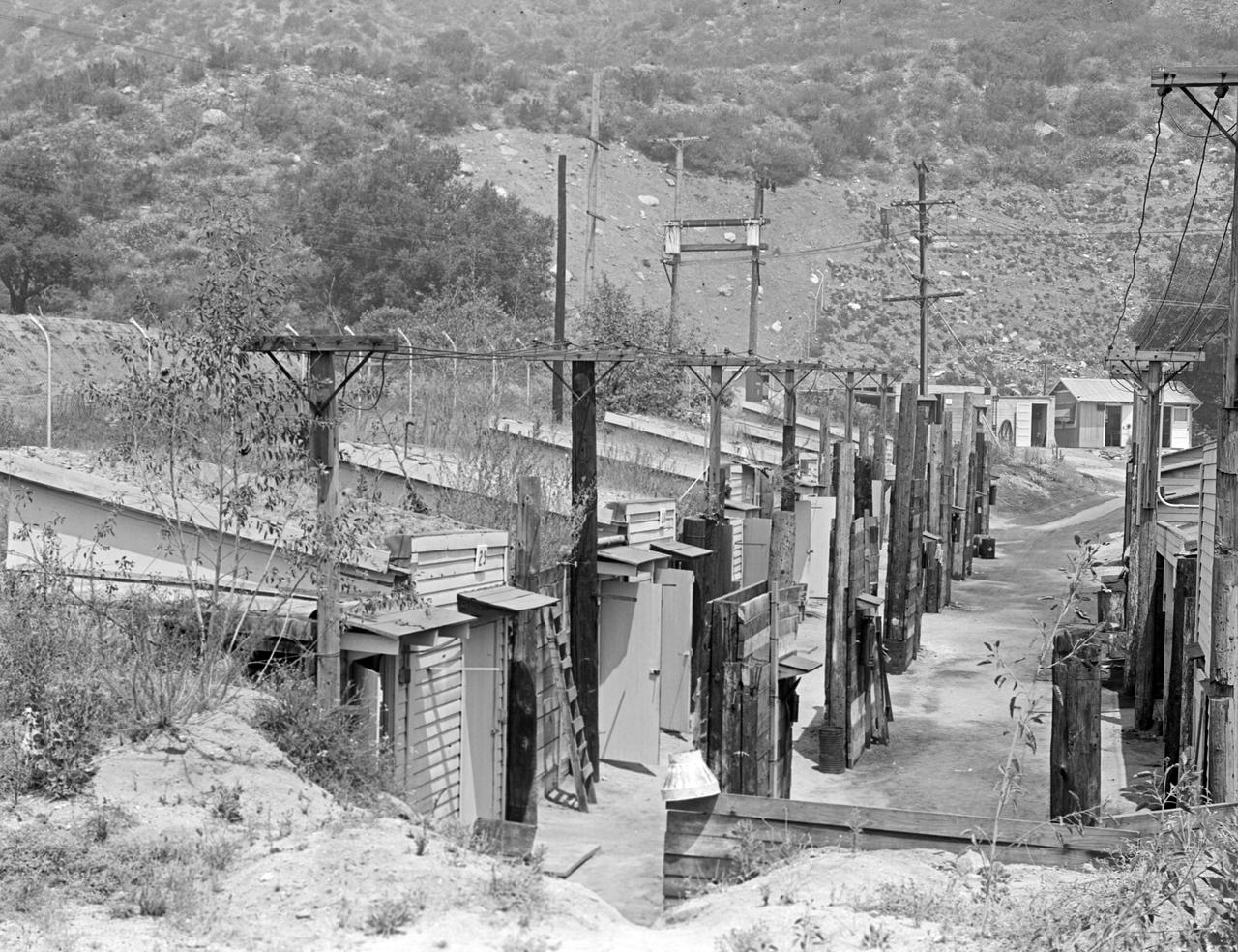 This archival image was released as part of a gallery comparing JPL's past and present, commemorating the 80th anniversary of NASA's Jet Propulsion Laboratory on Oct. 31, 2016.  At the northeast end of the Jet Propulsion Laboratory, there was a row of rocket test pits and storage buildings that housed explosives. This was near the Arroyo Seco, a dry canyon wash at the base of the San Gabriel Mountains. The picture was taken in August 1944. Today, this area is a small parking lot behind the Fabrication Shop (Building 103).  http://photojournal.jpl.nasa.gov/catalog/PIA21119