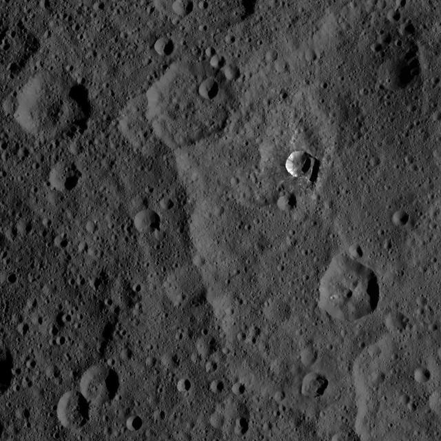 The 6-mile-wide (10-kilometer-wide) Oxo Crater stands out on the dark landscape of Ceres in this view from NASA's Dawn spacecraft. Oxo is one of several sites at which ice has been identified by Dawn's visible and infrared mapping spectrometer. The crater is located at mid-latitudes (42 degrees North, 0 degrees East), and the presence of ice there is consistent with the recent mapping of hydrogen by Dawn's GRaND instrument (Gamma Ray and Neutron Detector). Ice is likely to be present at shallow depths in this region, waiting to be exposed via small impacts or landslides, as is believed to be the case for Oxo. Ice is not stable for long periods of time on Ceres' surface, thus its exposure at Oxo must be a relatively recent event. Dawn took this image on Oct. 25, 2016, during its second extended-mission science orbit (XMO2), from a distance of about 920 miles (1,480 kilometers) above the surface of Ceres. The image resolution is about 460 feet (140 meters) per pixel. http://photojournal.jpl.nasa.gov/catalog/PIA21250