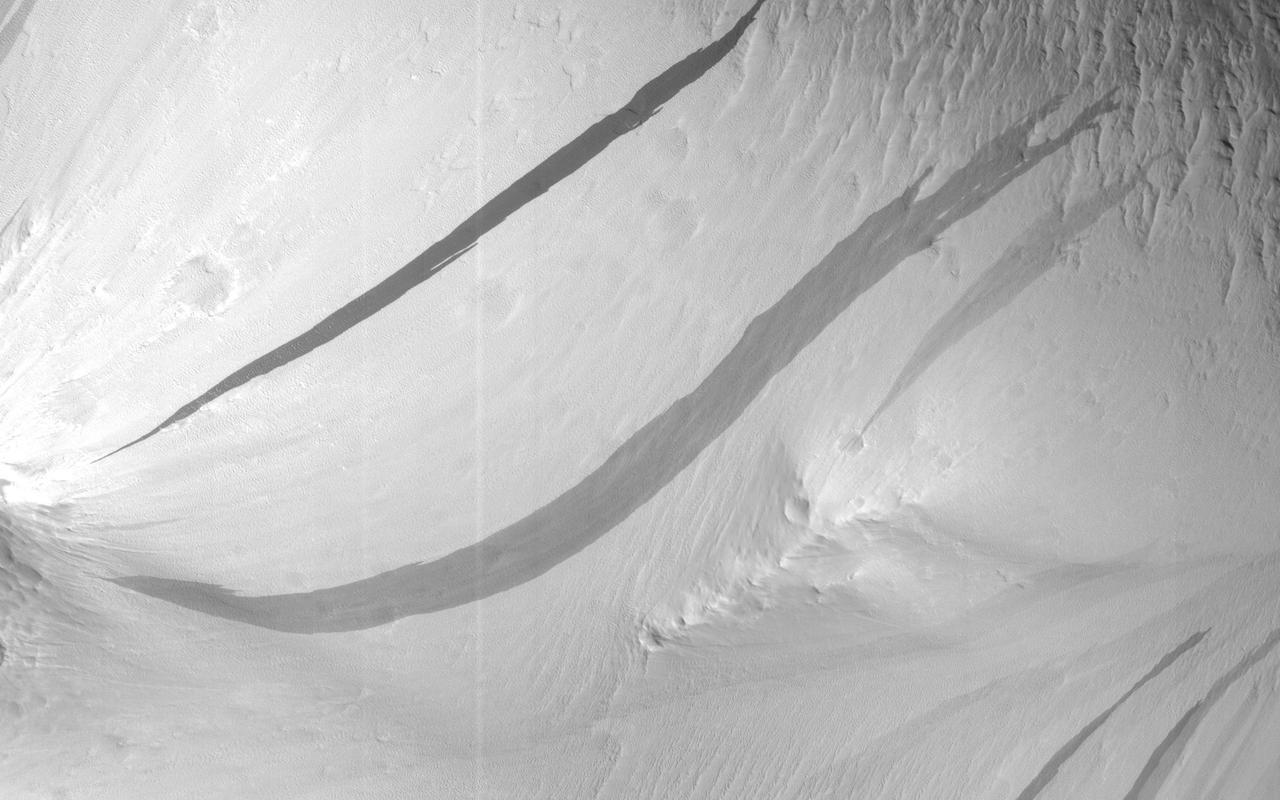 The image shows a region we see many slope streaks, typically dark features on slopes in the equatorial regions on Mars. They may extend for tens of meters in length and gradually fade away with time as new ones form. The most common hypothesis is that they are generated by dust avalanches that regularly occur on steep slopes exposing fresh dark materials from underneath the brighter dust.  There are many types of slope streaks but one of the most recent and significant findings using HiRISE was the discovery of a new type called "recurring slope lineae," or RSL for short. Recent studies suggest that RSL may form through the flow of briny (extremely salty) liquid water that can be stable on the surface of Mars even under current climatic conditions for a limited time in summer when it is relatively warm.  How can we distinguish between conventional slope streaks like the ones we see here and RSL? There are many criteria. For instance, RSL are usually smaller in size than regular slope streaks. However, one of the most important conditions is seasonal behavior, since RSL appear to be active only in summer while regular slope streaks can be active anytime of the year.  This site is monitored regularly by HiRISE scientists because of the high density of slope streaks and their different sizes and orientations. If we look at a time-lapse sequence, we will see that a new slope streak has indeed formed in the period since April 2016 (and we can note how dark it is in comparison to the others indicating its freshness). However, this period corresponds mainly to the autumn season in this part of Mars, whereas we do not see any major changes in the summer season. This suggests that the feature that developed is a regular slope streak just like all the others in the area.  http://photojournal.jpl.nasa.gov/catalog/PIA21272
