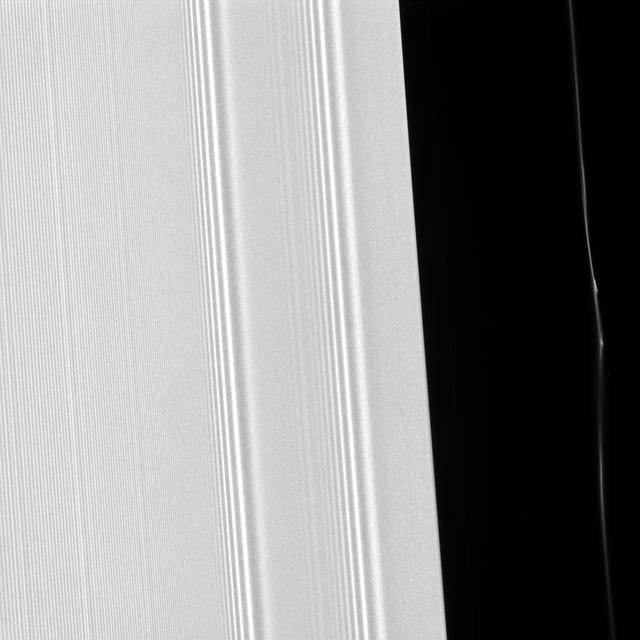 Many of the features seen in Saturn's rings are shaped by the planet's moons. This view from NASA's Cassini spacecraft shows two different effects of moons that cause waves in the A ring and kinks in a faint ringlet. The view captures the outer edge of the 200-mile-wide (320-kilometer-wide) Encke Gap, in the outer portion of Saturn's A ring. This is the same region features the large propeller called Earhart. Also visible here is one of several kinked and clumpy ringlets found within the gap. Kinks and clumps in the Encke ringlet move about, and even appear and disappear, in part due to the gravitational effects of Pan -- which orbits in the gap and whose gravitational influence holds it open. The A ring, which takes up most of the image on the left side, displays wave features caused by Pan, as well as the moons Pandora and Prometheus, which orbit a bit farther from Saturn on both sides of the planet's F ring. This view was taken in visible light with the Cassini spacecraft narrow-angle camera on March 22, 2017, and looks toward the sunlit side of the rings from about 22 degrees above the ring plane. The view was acquired at a distance of approximately 63,000 miles (101,000 kilometers) from Saturn and at a phase angle (the angle between the sun, the rings and the spacecraft) of 59 degrees. Image scale is 1,979 feet (603 meters) per pixel. https://photojournal.jpl.nasa.gov/catalog/PIA21333