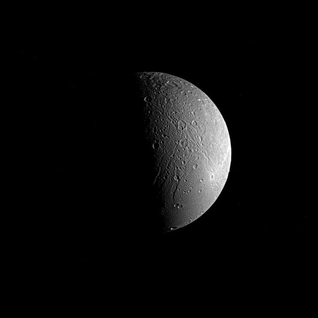 Saturn's moon Dione is captured in this view from NASA's Cassini spacecraft, half in shadow and half in light. Sinuous canyons carve interconnected paths across the moon's icy landscape. Subtle variations in brightness hint at differences in composition, as well as the size and shape of grains in Dione's surface material, or regolith.  Cassini spent more than a decade at Saturn studying Dione (698 miles or 1,123 kilometers across) and the planet's many other moons as part of the quest to understand how the moons formed and evolved, and how they are connected.  This view looks toward the side of Dione that faces away from Saturn. North is up and rotated 59 degrees to the right. The image was taken in visible light with the Cassini spacecraft narrow-angle camera on June 22, 2017.  The view was obtained at a distance of approximately 224,000 miles (360,000 kilometers) from Dione. Image scale is 1.4 mile (2.2 kilometers) per pixel.  The Cassini spacecraft ended its mission on Sept. 15, 2017.  https://photojournal.jpl.nasa.gov/catalog/PIA21349