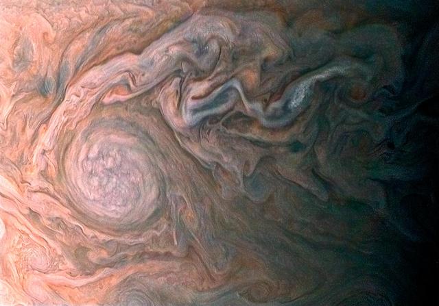 NASA Juno spacecraft skimmed the upper wisps of Jupiter atmosphere when JunoCam snapped this image on Feb. 2, 2017. from an altitude of about 9,000 miles 14,500 kilometers above the giant planet swirling cloudtops.  Streams of clouds spin off a rotating oval-shaped cloud system in the Jovian southern hemisphere. Citizen scientist Roman Tkachenko reconstructed the color and cropped the image to draw viewers' eyes to the storm and the turbulence around it.   http://photojournal.jpl.nasa.gov/catalog/PIA21383  .  -    Enhanced image by Roman Tkachenko (CC-BY) based on images provided courtesy of NASA/JPL-Caltech/SwRI/MSSS