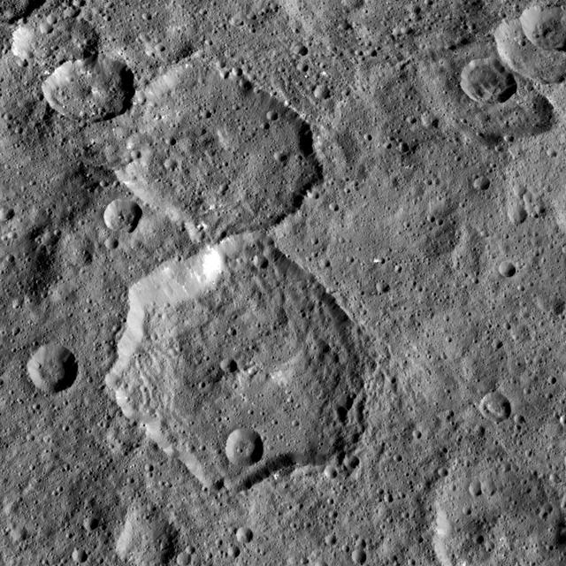 NASA's Dawn mission has found that craters on Ceres show a diversity of shapes that provide important clues about the structure of Ceres' subsurface. The bottom half of this pair of craters is called Fejokoo, named after the Nigerian god who supplied yams. The hexagonal shape of that 42-mile (68-kilometer) crater is probably due to the presence of fractures in the crust, along which the crater rims tend to align. Polygonal craters are frequent on Ceres. Most display six or seven sides, like in the case of Fejokoo, but a few nonagons -- nine-sided shapes -- have been discovered. Polygonal craters are also commonly found on other solar system bodies, such as Mars, Earth's moon and icy moons of giant planets. Dawn took this image on May 4, 2015, from an altitude of 915 miles (1,470 kilometers). The image has a resolution of 450 feet (140 meters) per pixel. http://photojournal.jpl.nasa.gov/catalog/PIA21399