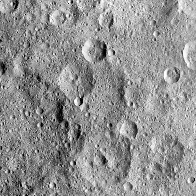 NASA's Dawn spacecraft took this image of Hakumyi Crater on Ceres, visible left of center. The crater is named after a Paraguayan, Brazilian and Bolivian spirit said to be helpful in gardening. Hakumyi, 18 miles (29 kilometers) in diameter, is located about 43 miles (70 kilometers) west of Ernutet Crater. Ernutet is where scientists found evidence of organic material, thanks to Dawn's visible and infrared mapping spectrometer. Evidence for organics was also found at the 4-mile (6.5 kilometer) wide fresh crater on the southern rim of Hakumyi and on the lobe-shaped flow of material that runs into Hakumyi. These two features look relatively young in comparison to the rest of Hakumyi Crater, whose rims and overall shape are subdued. The lobate flow is reminiscent of the Type I flows identified in multiple places at high latitudes on Ceres, and suggests a significant amount of ice near the surface. Dawn took this image on August 20, 2015, from 915 miles (1,470 kilometers) altitude. The center coordinates of this image are 48.9 degrees north latitude and 27.0 degrees east longitude. https://photojournal.jpl.nasa.gov/catalog/PIA21413