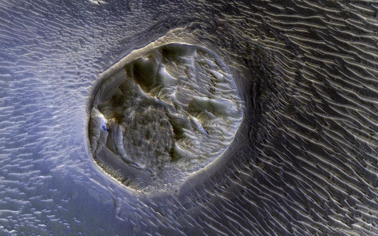 This image from NASA's Mars Reconnaissance Orbiter shows a small (0.4 kilometer) mesa, one of several surrounded by sand dunes in Noctis Labyrinthyus, an extensively fractured region on the western end of Valles Marineris.  Heavily eroded, with clusters of boulders and sand dunes on its surface, this layered mesa is probably comprised of sedimentary deposits that are being exhumed as it erodes. The layers themselves are visible as faint bands along the lower left edge of the mesa.  The map is projected here at a scale of 50 centimeters (19.7 inches) per pixel. [The original image scale is 20.7 centimeters (19.6 inches) per pixel (with 2 x 2 binning); objects on the order of 158 centimeters (62.2 inches) across are resolved.] North is up.  https://photojournal.jpl.nasa.gov/catalog/PIA21585
