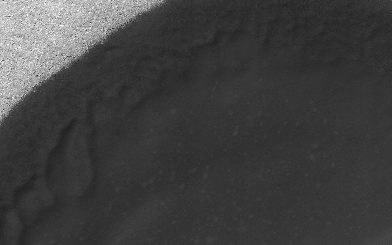Sand dune populations on Mars can vary widely with respect to morphology, relief, and activity. One of the most striking examples occurs with the many dune fields of the high Southern latitudes. When we venture south of -60 degrees latitude, we see increasing signs of dune degradation, with subdued dune brinks and broad sandy aprons, rather than sharp, dune crests and distinct boundaries. Dunes this far south are also very modest in height, often consisting solely of flat sand sheets. Additionally, global monitoring campaigns are revealing a noticeable lack of changes in these bedform positions, whereas many dunes and ripples to the north are migrating across the surface. This image shows a moderate sized dune field (-72 degrees latitude) that displays most of these morphologic features and a noticeable absence of dune crests. This transition is likely related to polar processes, ground ice, and changes in regional climate relative to the rest of the planet. https://photojournal.jpl.nasa.gov/catalog/PIA21595