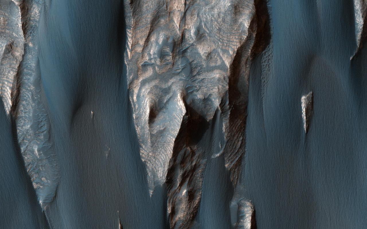 Dark, windblown sand covers intricate sedimentary rock layers in this image captured by NASA's Mars Reconnaissance Orbiter (MRO) from Ganges Chasma, a canyon in the Valles Marineris system.  These features are at once familiar and unusual to those familiar with Earth's beaches and deserts. Most sand dunes on Earth are made of silica-rich sand, giving them a light color; these Martian dunes owe their dark color to the iron and magnesium-rich sand found in the region.  https://photojournal.jpl.nasa.gov/catalog/PIA21600