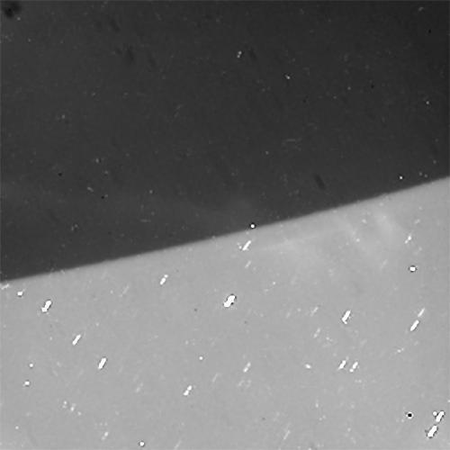 Cassini gazed toward high southern latitudes near Saturn's south pole to observe ghostly curtains of dancing light -- Saturn's southern auroras, or southern lights. These natural light displays at the planet's poles are created by charged particles raining down into the upper atmosphere, making gases there glow.  The dark area at the top of this scene is Saturn's night side. The auroras rotate from left to right, curving around the planet as Saturn rotates over about 70 minutes, compressed here into a movie sequence of about five seconds.  Background stars are seen sliding behind the planet. Cassini was moving around Saturn during the observation, keeping its gaze fixed on a particular spot on the planet, which causes a shift in the distant background over the course of the observation.  Some of the stars seem to make a slight turn to the right just before disappearing. This effect is due to refraction -- the starlight gets bent as it passes through the atmosphere, which acts as a lens.  Random bright specks and streaks appearing from frame to frame are due to charged particles and cosmic rays hitting the camera detector.  The aim of this observation was to observe seasonal changes in the brightness of Saturn's auroras, and to compare with the simultaneous observations made by Cassini's infrared and ultraviolet imaging spectrometers.  The original images in this movie sequence have a size of 256x256 pixels; both the original size and a version enlarged to 500x500 pixels are available here. The small image size is the result of a setting on the camera that allows for shorter exposure times than full-size (1024x1024 pixel) images. This enabled Cassini to take more frames in a short time and still capture enough photons from the auroras for them to be visible.  The images were taken in visible light using the Cassini spacecraft narrow-angle camera on July 20, 2017, at a distance of about 620,000 miles (1 million kilometers) from Saturn. The views look toward 74 degrees south latitude on Saturn. Image scale is about 0.9 mile (1.4 kilometers) per pixel on Saturn.  An animation is available at https://photojournal.jpl.nasa.gov/catalog/PIA21623