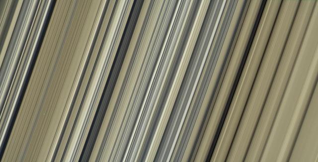 These are the highest-resolution color images of any part of Saturn's rings, to date, showing a portion of the inner-central part of the planet's B Ring. The view is a mosaic of two images that show a region that lies between 61,300 and 65,600 miles (98,600 and 105,500 kilometers) from Saturn's center.  This image is a natural color composite, created using images taken with red, green and blue spectral filters. The pale tan color is generally not perceptible with the naked eye in telescope views, especially given that Saturn has a similar hue.  The material responsible for bestowing this color on the rings -- which are mostly water ice and would otherwise appear white -- is a matter of intense debate among ring scientists that will hopefully be settled by new in-situ observations before the end of Cassini's mission.  The different ringlets seen here are part of what is called the "irregular structure" of the B ring. Cassini radio occultations of the rings have shown that these features have extremely sharp boundaries on even smaller scales (radially, or along the direction outward from Saturn) than the camera can resolve here. Closer to Saturn, the irregular structures become fuzzier and more rounded, less opaque, and their color contrast diminishes.  The narrow ringlets in the middle of this scene are each about 25 miles (40 kilometers) wide, and the broader bands at right are about 200 to 300 miles (300 to 500 kilometers) across. It remains unclear exactly what causes the variable brightness of these ringlets and bands -- the basic brightness of the ring particles themselves, shadowing on their surfaces, their absolute abundance, and how densely the particles are packed, may all play a role.  The second image (Figure 1) is a color-enhanced version. Blue colors represent areas where the spectrum at visible wavelengths is less reddish (meaning the spectrum is flatter toward red wavelengths), while red colors represent areas that are spectrally redder (meaning the spectrum has a steeper spectrum toward red wavelengths). Observations from the Voyager mission and Cassini's visual and infrared mapping spectrometer previously showed these color variations at lower resolution, but it was not known that such well-defined color contrasts would be this sharply defined down to the scale (radial scale) of a couple of miles or kilometers, as seen here.  Analysis of additional images from this observation, taken using infrared spectral filters sensitive to absorption of light by water ice, indicates that the areas that appear more visibly reddish in the color-enhanced version are also richer in water ice.  The third image (Figure 2) is a composite of the "true" and "enhanced" color images for easy comparison.  This image was taken on July 6, 2017, with the Cassini spacecraft narrow-angle camera. The image was acquired on the sunlit side of the rings from a distance of 47,000 miles (76,000 kilometers) away from the area pictured. The image scale is about 2 miles (3 kilometers) per pixel. The phase angle, or sun-ring-spacecraft angle, is 90 degrees.  https://photojournal.jpl.nasa.gov/catalog/PIA21628