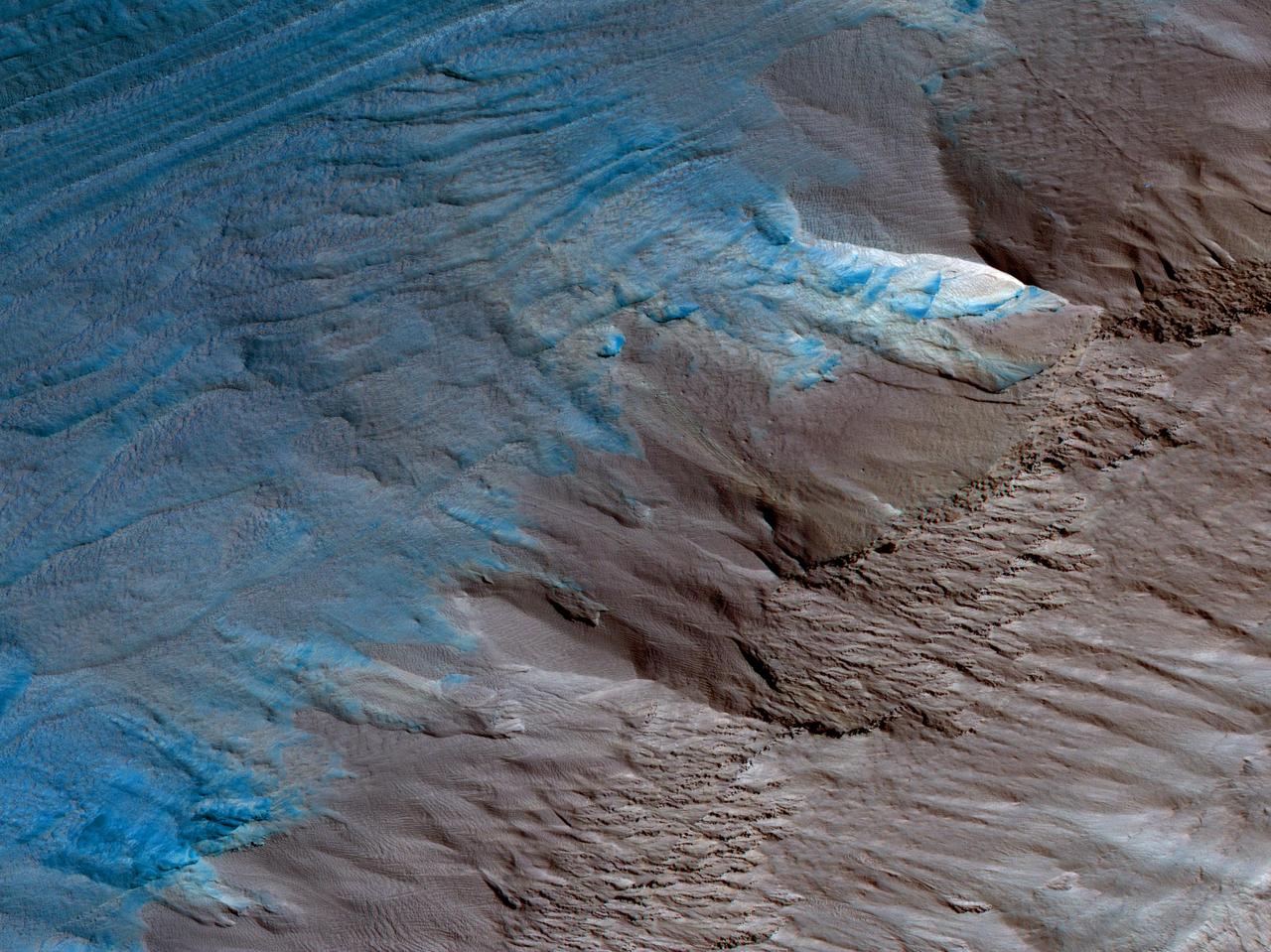 This image is an oblique view from NASA's Mars Reconnaissance Orbiter of the sloping edge of the stack of icy layers over the South Pole has some interesting morphologies.  The slope appears to be eroding from a combination of landslides, block falls, and sublimation. The bright icy exposure in the larger landslide scar (upper right) suggests that this was a relatively recent event.  Small-scale textures over the scene are due to both blowing wind and the thermal expansion and contraction of shallow ice.  https://photojournal.jpl.nasa.gov/catalog/PIA21637