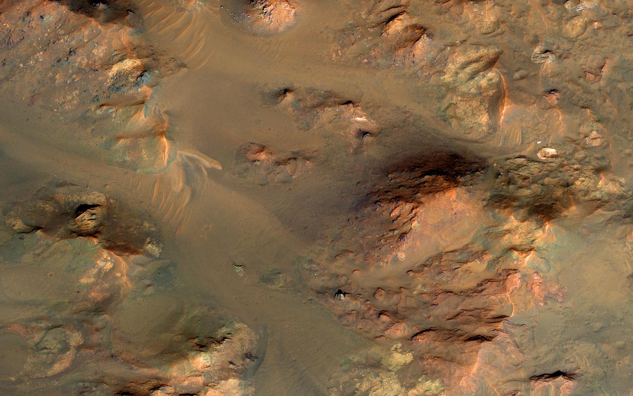 This image from NASA's Mars Reconnaissance Orbiter shows part of the central uplifted region of an impact crater more than 50 kilometers wide. That means that the bedrock has been raised from a depth of about 5 kilometers, exposing ancient materials. The warm (yellowish-reddish) colors mark the presence of minerals altered by water, whereas the bluish and greenish rocks have escaped alteration. Sharp-crested ridges and smooth areas are young windblown materials. https://photojournal.jpl.nasa.gov/catalog/PIA21640