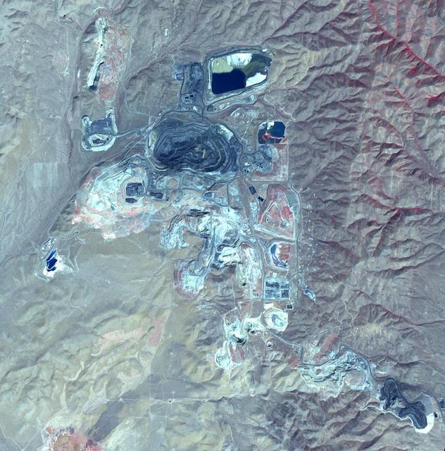 This image from NASA Terra spacecraft shows Goldstrike in northeast Nevada, the largest gold mine in North America. The mine complex, (including the Betze-Post-Screamer open-pit, and Meikle and Rodeo underground mines) is owned and operated by the world's largest gold mining company, Barrick Gold. Gold occurs as microscopically fine grains, with an average grade of 0.1 ounces per ton of ore. Estimates of reserves are as high as 35 million ounces of gold. The image was acquired September 25, 2010, covers an area of 15 by 15 km, and is located at 41 degrees north, 116.4 degrees west.  https://photojournal.jpl.nasa.gov/catalog/PIA21665