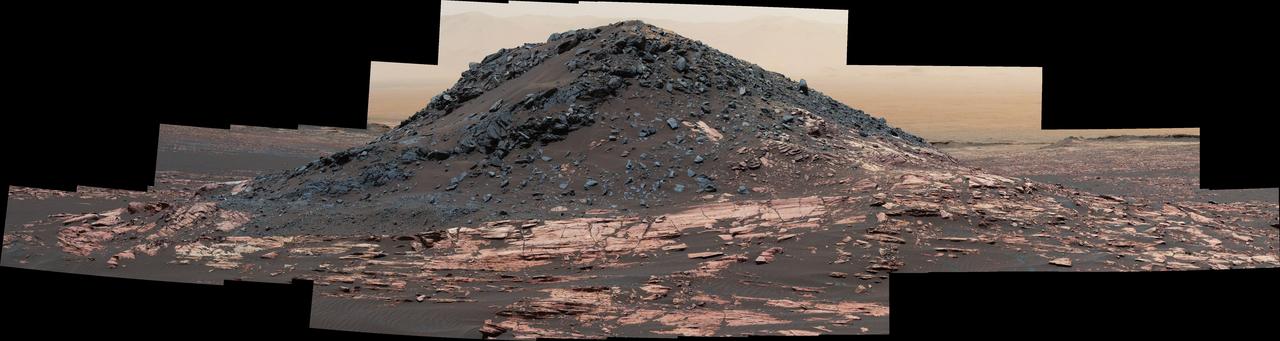 This dark mound, called "Ireson Hill," rises about 16 feet (5 meters) above redder layered outcrop material of the Murray formation on lower Mount Sharp, Mars, near a location where NASA's Curiosity rover examined a linear sand dune in February 2017.  Researchers used the rover's Mast Camera (Mastcam) on Feb. 2, 2017, during the 1,598th Martian day, or sol, of Curiosity's work on Mars, to take the 41 images combined into this scene. The mosaic has been white-balanced so that the colors of the rock and sand materials resemble how they would appear under daytime lighting conditions on Earth. The view extends from west-southwest on the left to north-northwest on the right. The faint horizon in the distance beyond Ireson Hill is part of the rim of Gale Crater.  An annotated figure is available at https://photojournal.jpl.nasa.gov/catalog/PIA21718
