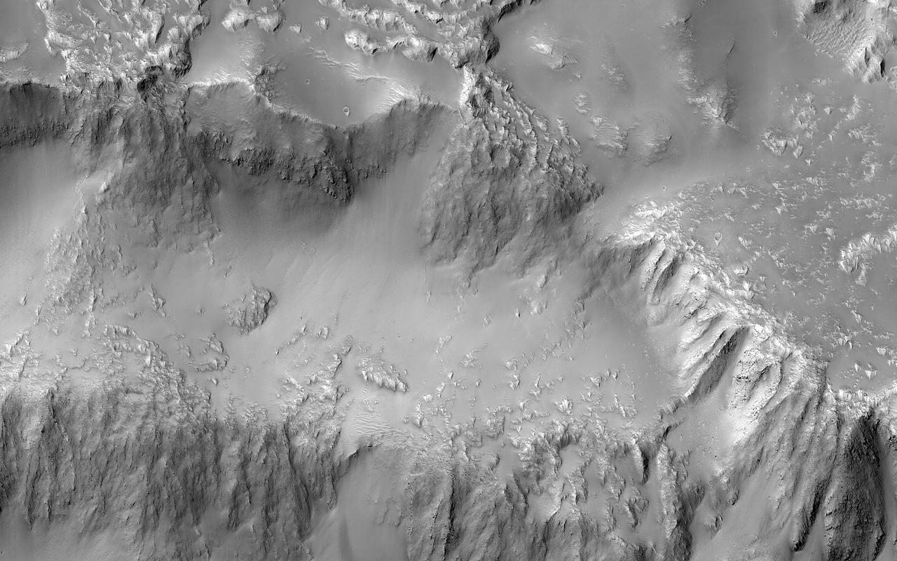 Various researchers are often pre-occupied with the quest for flowing water on Mars. However, this image from NASA's Mars Reconnaissance Orbiter (MRO), shows one of the many examples from Mars where lava (when it was molten) behaved in a similar fashion to liquid water.  The northern rim of a 30-kilometer diameter crater situated in the western part of the Tharsis volcanic province is shown. The image shows that a lava flow coming from the north-northeast surrounded the crater rim, and rose to such levels that it breached the crater rim at four locations to produce spectacular multi-level lava falls (one in the northwest and three in the north). These lava "falls" cascaded down the wall and terraces of the crater to produce a quasi-circular flow deposit. It seems that the flows were insufficient to fill or even cover the pre-existing deposits of the crater floor. This is evidenced by the darker-toned lavas that overlie the older, and possibly dustier, lighter-toned deposits on the crater floor.  This image covers the three falls in the north-central region of the crater wall. The lava flows and falls are distinct as they are rougher than the original features that are smooth and knobby. In a close-up image the rough-textured lava flow to the north has breached the crater wall at a narrow point, where it then cascades downwards, fanning out and draping the steeper slopes of the wall in the process.  Image scale is 54.5 centimeters (21.5 inches) per pixel (with 2 x 2 binning); objects on the order of 164 centimeters (64.6 inches) across are resolved.] North is up.  https://photojournal.jpl.nasa.gov/catalog/PIA21763