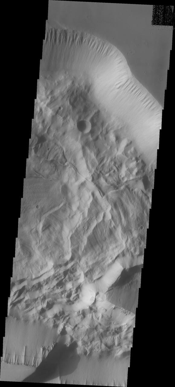 This image shows the eastern portion of Hebes Chasma. The ridge that is casting a shadow at the bottom of the image is likely a large tectonic fault. All of the materials on the floor of the chasma are from the cliff faces. The deposition and erosion of the materials in this image are very different from the those of the large central mesa. Hebes Chasma is an enclosed basin not connected to Valles Marineris.  The Odyssey spacecraft has spent over 15 years in orbit around Mars, circling the planet more than 69000 times. It holds the record for longest working spacecraft at Mars. THEMIS, the IR/VIS camera system, has collected data for the entire mission and provides images covering all seasons and lighting conditions. Over the years many features of interest have received repeated imaging, building up a suite of images covering the entire feature. From the deepest chasma to the tallest volcano, individual dunes inside craters and dune fields that encircle the north pole, channels carved by water and lava, and a variety of other feature, THEMIS has imaged them all. For the next several months the image of the day will focus on the Tharsis volcanoes, the various chasmata of Valles Marineris, and the major dunes fields. We hope you enjoy these images!  Orbit Number: 27124 Latitude: -1.43316 Longitude: 285.942 Instrument: VIS Captured: 2008-01-25 15:05  https://photojournal.jpl.nasa.gov/catalog/PIA21816