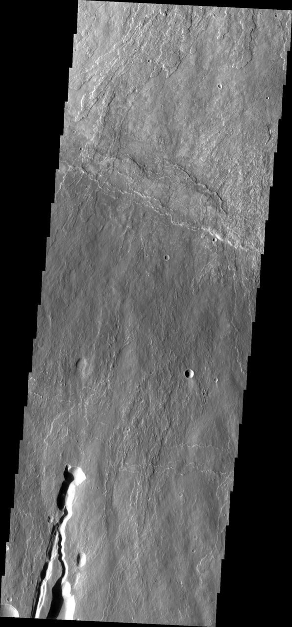 This image shows part of the southern flank of Ascraeus Mons. The feature at the bottom of the image is a collapse feature. These features can be caused by several processes. The ceiling of lava tubes can collapse into the open space left after the last flow. Tectonic activity can occur, and blocks of material can drop down between faults. The tectonic features are called graben. All three of the Tharsis volcanoes (Ascraeus, Pavonis and Arsia mons) are aligned along a northeast/southwest trend. The largest region of collapse features on each of the three volcanoes are located along this trend. The Odyssey spacecraft has spent over 15 years in orbit around Mars, circling the planet more than 69000 times. It holds the record for longest working spacecraft at Mars. THEMIS, the IR/VIS camera system, has collected data for the entire mission and provides images covering all seasons and lighting conditions. Over the years many features of interest have received repeated imaging, building up a suite of images covering the entire feature. From the deepest chasma to the tallest volcano, individual dunes inside craters and dune fields that encircle the north pole, channels carved by water and lava, and a variety of other feature, THEMIS has imaged them all. For the next several months the image of the day will focus on the Tharsis volcanoes, the various chasmata of Valles Marineris, and the major dunes fields. We hope you enjoy these images! Orbit Number: 18376 Latitude: 9.77446 Longitude: 254.826 Instrument: VIS Captured: 2006-02-04 10:32 https://photojournal.jpl.nasa.gov/catalog/PIA21824