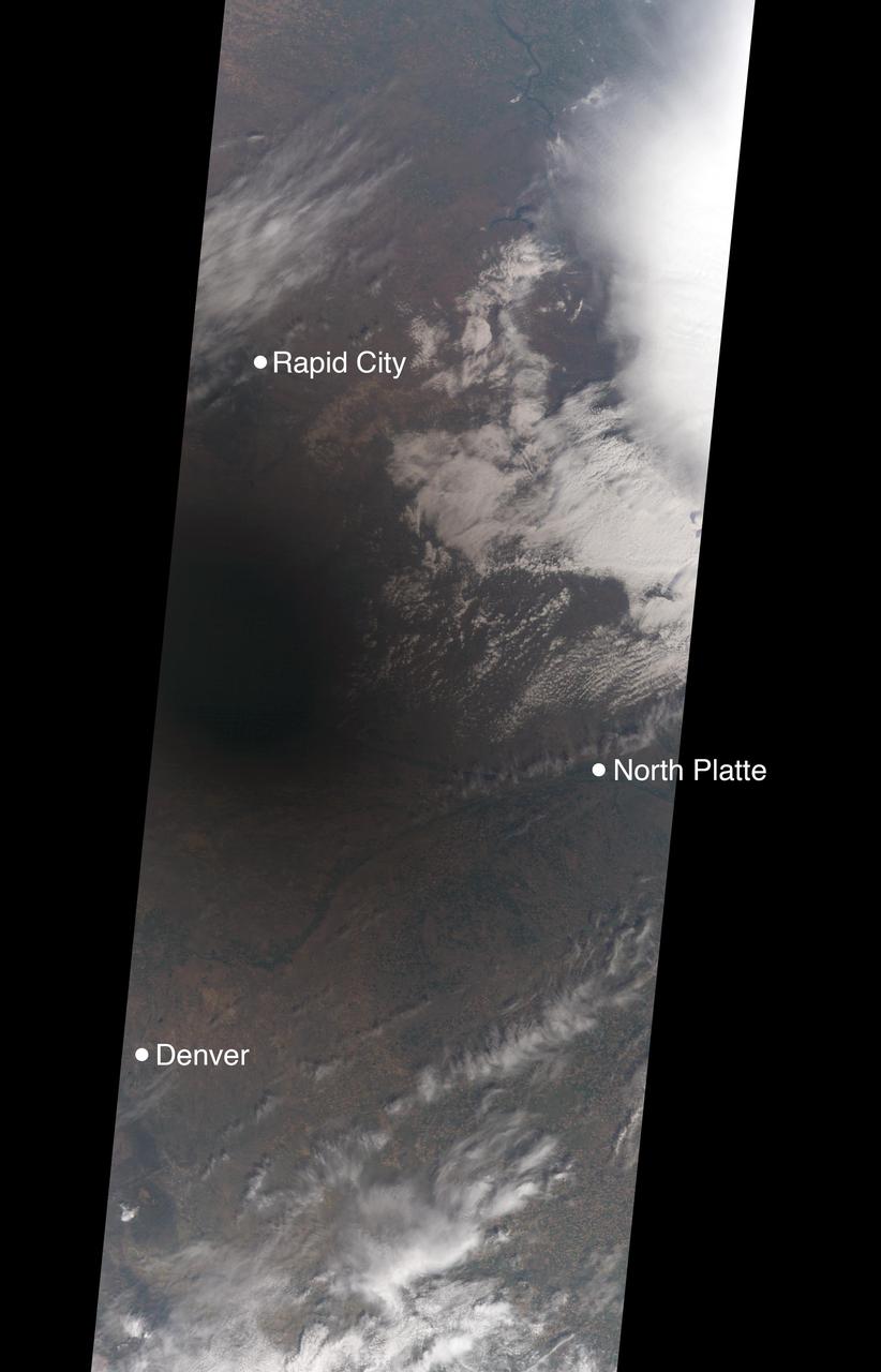 On Aug. 21, 2017, a total solar eclipse swept across the United States -- the first such eclipse in the contiguous 48 states since 1979, and the first cross-country eclipse since 1918. A partial eclipse was visible in all 50 states, and initial estimates suggest that upwards of 20 million people observed the Moon completely obscuring the Sun in the 70-mile-wide (113-kilometer-wide) path of totality. While viewing a total solar eclipse from the ground is an amazing experience, satellites orbiting Earth see the eclipse from a unique perspective.  As the Moon's shadow passed through the United States, the Multi-angle Imaging SpectroRadiometer (MISR) instrument aboard NASA's Terra satellite was capturing images of eastern Wyoming and western Nebraska from its altitude of 438 miles (705 kilometers) above the surface. MISR gathers images on a strip about 249 miles (400 kilometers) wide directly below the path of the satellite. Incredibly, given that the shadow of the Moon took only 90 minutes to cross the entire United States, and Terra itself moves at a brisk 16,700 miles per hour from north to south, MISR happened to be in exactly the right place at the right time to capture totality.  From the ground, the moment of totality appears suddenly, sweeping over the sky in just a few seconds. "I was unprepared for just how dark it actually was," says Mika Tosca, a researcher who works with MISR data and who observed the eclipse in Nebraska. "The streetlights even turned on. Everything fell silent, and I swear the temperature dropped." From the vantage point of space, however, it’s possible to see the entire shadow of the Moon, with the completely dark, circular umbra and the more diffuse penumbra.  MISR contains nine cameras oriented at different angles, viewing forward, downward, and backward along the flight path, resulting in an approximate seven-minute interval for all nine cameras to image a single location on Earth's surface. This animation combines these nine images into a movie showing the motion of the Moon's shadow during this seven-minute period.  In the first image, captured by the camera pointing farthest ahead of the satellite, totality has not quite begun in the area seen by MISR. From the second camera onward, totality sweeps across the image area from west to east, beginning just west of the town of Jay Em, Wyoming, and proceeding about halfway across the MISR swath to the town of Alliance, Nebraska. The motion of the lunar shadow in different pairs of images leads to estimates of the local ground speed ranging between 1,480 and 1,820 miles per hour (2,382 and 2,929 kilometers per hour). The spread in values is a measure of the uncertainty of the estimate. At this location, the predicted speed of the eclipse calculated from lunar orbital motion is about 1,658 miles per hour (2,668 kilometers per hour), which falls in the middle of the range estimated from the MISR images.  Tosca's observation that the temperature dropped during the eclipse is a well-known phenomenon. The GLOBE Observer, a phone application dedicated to citizen science and sponsored by NASA, encouraged eclipse-goers to record the local air temperature at regular intervals. Data collected by nearby observers in the path of totality show that, on average, temperatures dropped by 9.3 degrees Fahrenheit (5.2 degrees Celsius) during the eclipse. This compares to an average of 5.4 degrees Fahrenheit drop measured at several Nebraska Mesonet weather stations within the path of totality.  The decrease in the amount of sunlight reaching Earth affected more than temperatures. Areas that get a large portion of their power from solar energy were naturally concerned about shortages during the eclipse -- the state of California, though not in the path of totality, estimated that 6,000 megawatts of solar power would be lost during the eclipse.  An animation is available at https://photojournal.jpl.nasa.gov/catalog/PIA21957