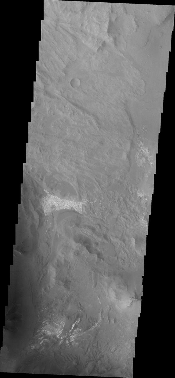 Coprates Chasma is one of the numerous canyons that make up Valles Marineris. The chasma stretches for 960 km (600 miles) from Melas Chasma to the west and Capri Chasma to the east. Landslide deposits, layered materials and sand dunes cover a large portion of the chasma floor. This image is located in eastern Coprates Chasma, just east of the previous image. In this image, the lobate margins of several landslide deposits are easy to identify. This indicates the chaotic surface in yesterday's image are materials emplaced by landslides. The brighter features at the bottom of the image are layered materials. There are also dunes in the region with the layered deposits. The Odyssey spacecraft has spent over 15 years in orbit around Mars, circling the planet more than 69000 times. It holds the record for longest working spacecraft at Mars. THEMIS, the IR/VIS camera system, has collected data for the entire mission and provides images covering all seasons and lighting conditions. Over the years many features of interest have received repeated imaging, building up a suite of images covering the entire feature. From the deepest chasma to the tallest volcano, individual dunes inside craters and dune fields that encircle the north pole, channels carved by water and lava, and a variety of other feature, THEMIS has imaged them all. For the next several months the image of the day will focus on the Tharsis volcanoes, the various chasmata of Valles Marineris, and the major dunes fields. We hope you enjoy these images! Orbit Number: 33037 Latitude: -13.8409 Longitude: 301.104 Instrument: VIS Captured: 2009-05-26 13:16 https://photojournal.jpl.nasa.gov/catalog/PIA21995