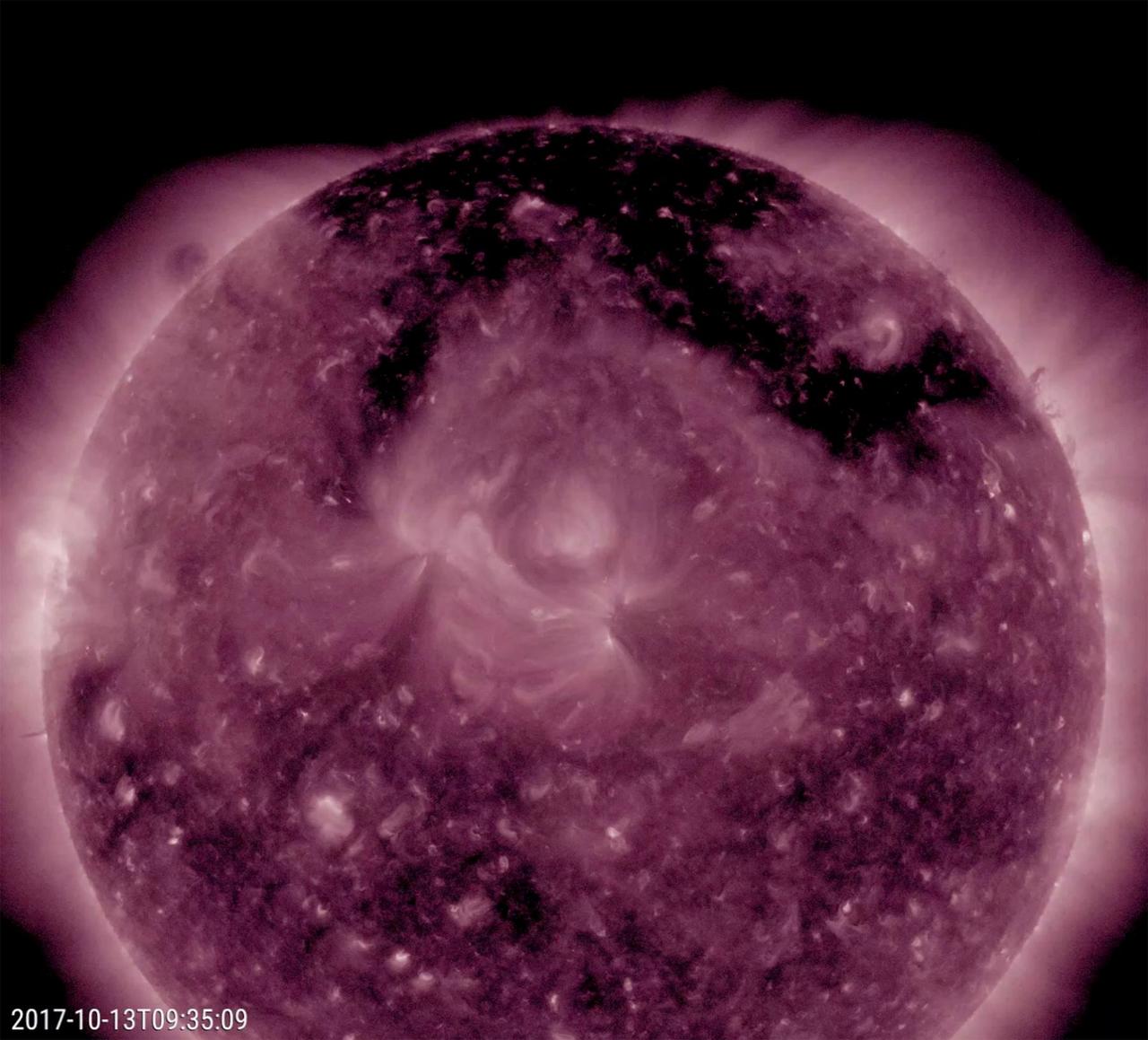 A large coronal hole stands out as the most obvious feature on the sun this week (Oct. 12-13, 2017). The dark structure, shaped kind of like the Pi symbol, spreads across much of the top of the sun. Though one cannot tell from this image and video clip in false-color extreme ultraviolet light, it is spewing high-speed solar wind particles into space and has been doing this all week. It is likely that these charged particles have been interacting with Earth's atmosphere and generating many aurora displays in regions near the poles the past several days.  Animations are available at https://photojournal.jpl.nasa.gov/catalog/PIA22047