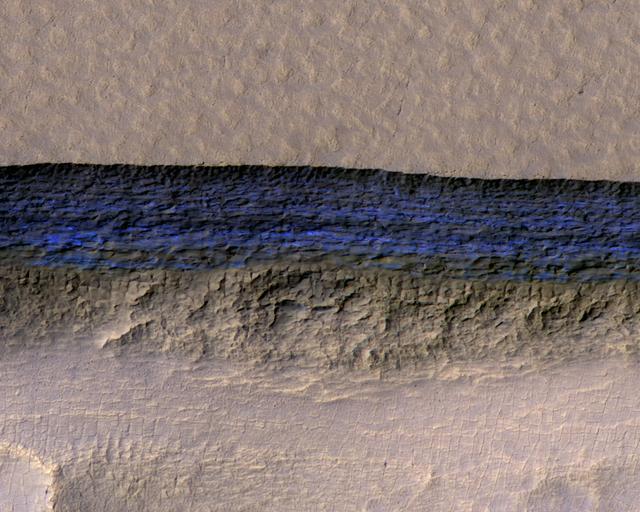 Click on the image for larger version A cross-section of a thick sheet of underground ice is exposed at the steep slope (or scarp) that appears bright blue in this enhanced-color view from the High Resolution Imaging Science Experiment (HiRISE) camera on NASA's Mars Reconnaissance Orbiter. The view covers an area about 550 yards (500 meters) wide. Figure 1 includes a 100-meter (109-yard) scale bar. North is toward the top. The upper third of the image shows level ground that is about 140 yards (130 meters) higher in elevation than the ground in the bottom third. In between, the scarp descends sharply, exposing about 260 vertical feet (80 vertical meters) of water ice. Color is exaggerated to make differences in surface materials easier to see. The presence of exposed water ice at this site was confirmed by observation with the same orbiter's Compact Reconnaissance Imaging Spectrometer for Mars (CRISM). In January 2018, in the journal Science, researchers reported finding and studying eight such ice-exposing scarps in the middle latitudes of Mars. The presence of vast underground ice deposits in Mars' middle latitudes was known previously. The report of unusual sites where they are exposed provides new information about their depth and layering. It also identifies potential water resources for future Mars missions and possibilities for studying Martian climate history by examining the ice layers holding a record of past climate cycles. The ice may have been deposited as snow when the tilt of Mars' rotation axis was greater than it is now. HiRISE observation ESP_022389_1230 was made on May 7, 2011, at 56.6 degrees south latitude, 114.1 degrees east longitude. https://photojournal.jpl.nasa.gov/catalog/PIA22077