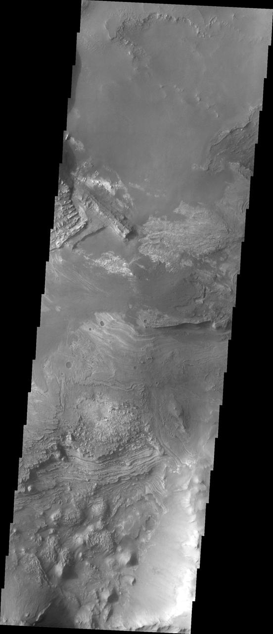Melas Chasma is part of the largest canyon system on Mars, Valles Marineris. At only 563 km long (349 miles) it is not the longest canyon, but it is the widest. Located in the center of Valles Marineris, it has depths up to 9 km below the surrounding plains, and is the location of many large landslide deposits, as will as layered materials and sand dunes. There is evidence of both water and wind action as modes of formation for many of the interior deposits. This VIS image highlights the extent of layered materials within the canyon. The image is located on the mid elevations on the south side of the canyon.  The Odyssey spacecraft has spent over 15 years in orbit around Mars, circling the planet more than 69000 times. It holds the record for longest working spacecraft at Mars. THEMIS, the IR/VIS camera system, has collected data for the entire mission and provides images covering all seasons and lighting conditions. Over the years many features of interest have received repeated imaging, building up a suite of images covering the entire feature. From the deepest chasma to the tallest volcano, individual dunes inside craters and dune fields that encircle the north pole, channels carved by water and lava, and a variety of other feature, THEMIS has imaged them all. For the next several months the image of the day will focus on the Tharsis volcanoes, the various chasmata of Valles Marineris, and the major dunes fields. We hope you enjoy these images!  Orbit Number: 10813 Latitude: -13.1037 Longitude: 289.967 Instrument: VIS Captured: 2004-05-22 16:09  https://photojournal.jpl.nasa.gov/catalog/PIA22129