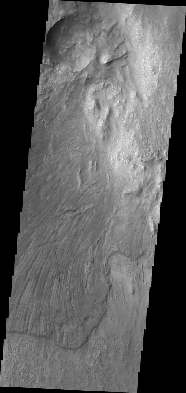 Melas Chasma is part of the largest canyon system on Mars, Valles Marineris. At only 563 km long (349 miles) it is not the longest canyon, but it is the widest. Located in the center of Valles Marineris, it has depths up to 9 km below the surrounding plains, and is the location of many large landslide deposits, as will as layered materials and sand dunes. There is evidence of both water and wind action as modes of formation for many of the interior deposits. This VIS image is located along the northern side of the chasma. The linear features are on the surface of a large landslide. This region of Melas Chasma is covered by several very large landslide deposits.  The Odyssey spacecraft has spent over 15 years in orbit around Mars, circling the planet more than 69000 times. It holds the record for longest working spacecraft at Mars. THEMIS, the IR/VIS camera system, has collected data for the entire mission and provides images covering all seasons and lighting conditions. Over the years many features of interest have received repeated imaging, building up a suite of images covering the entire feature. From the deepest chasma to the tallest volcano, individual dunes inside craters and dune fields that encircle the north pole, channels carved by water and lava, and a variety of other feature, THEMIS has imaged them all. For the next several months the image of the day will focus on the Tharsis volcanoes, the various chasmata of Valles Marineris, and the major dunes fields. We hope you enjoy these images!  Orbit Number: 36020 Latitude: -9.09641 Longitude: 288.172 Instrument: VIS Captured: 2010-01-27 03:51  https://photojournal.jpl.nasa.gov/catalog/PIA22138