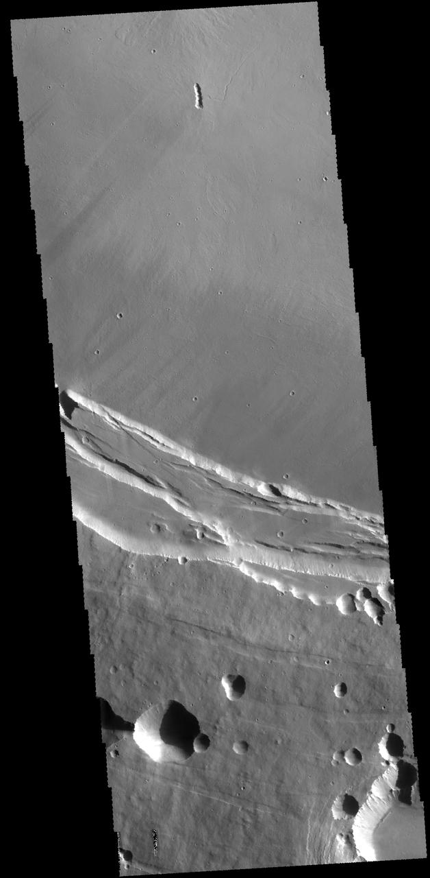 This THEMIS image shows part of the southern margin of the summit caldera. This image contains a variety of features representing the major events related to the formation of the volcano. At the top of the image a small linear vent has produced lava flows increasing the elevation of the surface around it. The flat floor of the caldera surrounds the vent and the cliff faces at the center of the image were created during the collapse event that formed the caldera. Depressions at the bottom illustrate collapse into empty voids like lava tubes.  Arsia Mons is the southernmost of the Tharsis volcanoes. It is 270 miles (450 km) in diameter, almost 12 miles (20 km) high, and the summit caldera is 72 miles (120 km) wide. For comparison, the largest volcano on Earth is Mauna Loa. From its base on the sea floor, Mauna Loa measures only 6.3 miles high and 75 miles in diameter. A large volcanic crater known as a caldera is located at the summit of all of the Tharsis volcanoes. These calderas are produced by massive volcanic explosions and collapse. The Arsia Mons summit caldera is larger than many volcanoes on Earth.  The Odyssey spacecraft has spent over 15 years in orbit around Mars, circling the planet more than 69000 times. It holds the record for longest working spacecraft at Mars. THEMIS, the IR/VIS camera system, has collected data for the entire mission and provides images covering all seasons and lighting conditions. Over the years many features of interest have received repeated imaging, building up a suite of images covering the entire feature. From the deepest chasma to the tallest volcano, individual dunes inside craters and dune fields that encircle the north pole, channels carved by water and lava, and a variety of other feature, THEMIS has imaged them all. For the next several months the image of the day will focus on the Tharsis volcanoes, the various chasmata of Valles Marineris, and the major dunes fields. We hope you enjoy these images!  Orbit Number: 63900 Latitude: -10.0873 Longitude: 239.197 Instrument: VIS Captured: 2016-05-10 07:58  https://photojournal.jpl.nasa.gov/catalog/PIA22159