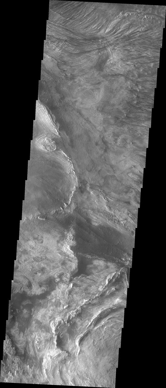 This image shows part of western Candor and the erosion of a large mesa. Layered materials are visible throughout the image. The dark material with the linear appearance in the middle of the image are sand dunes. Sand dunes are created by wind action. At the present time, wind is the active process shaping the surface.  Candor Chasma is one of the largest canyons that make up Valles Marineris. It is approximately 810 km long (503 miles) and has is divided into two regions - eastern and western Candor. Candor is located south of Ophir Chasma and north of Melas Chasma. The border with Melas Chasma contains many large landslide deposits. The floor of Candor Chasma includes a variety of landforms, including layered deposits, dunes, landslide deposits and steep sided cliffs and mesas. Many forms of erosion have shaped Chandor Chasma. There is evidence of wind and water erosion, as well as significant gravity driven mass wasting (landslides).  The Odyssey spacecraft has spent over 15 years in orbit around Mars, circling the planet more than 69000 times. It holds the record for longest working spacecraft at Mars. THEMIS, the IR/VIS camera system, has collected data for the entire mission and provides images covering all seasons and lighting conditions. Over the years many features of interest have received repeated imaging, building up a suite of images covering the entire feature. From the deepest chasma to the tallest volcano, individual dunes inside craters and dune fields that encircle the north pole, channels carved by water and lava, and a variety of other feature, THEMIS has imaged them all. For the next several months the image of the day will focus on the Tharsis volcanoes, the various chasmata of Valles Marineris, and the major dunes fields. We hope you enjoy these images!  Orbit Number: 6245 Latitude: -5.77639 Longitude: 284.339 Instrument: VIS Captured: 2003-05-12 14:49  https://photojournal.jpl.nasa.gov/catalog/PIA22161